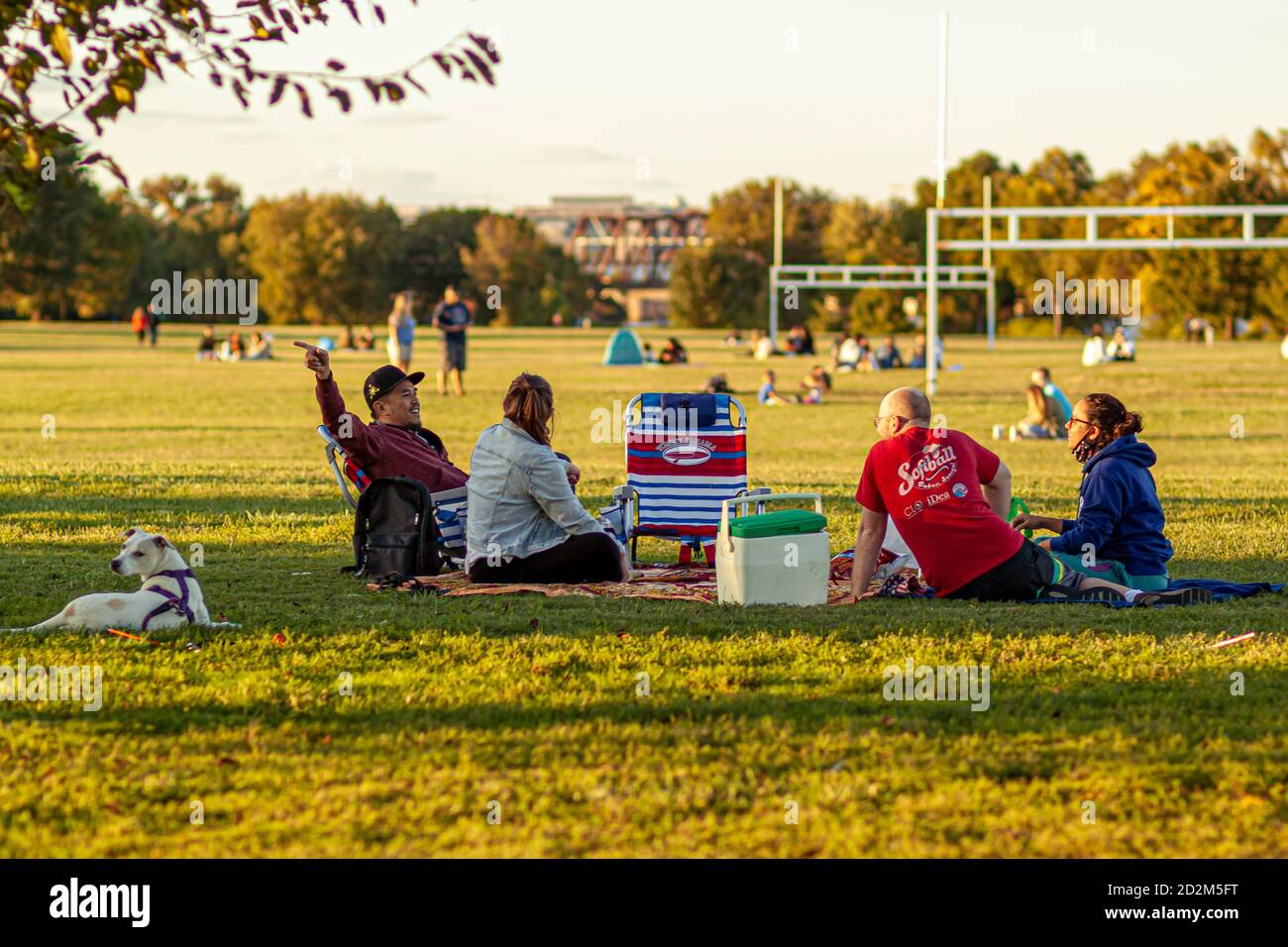 Arlington, VA, USA 10/02/2020: A multi racial group of young people are sitting on foldable chairs or sheets on grass field of Gravelly point park. Th Stock Photo