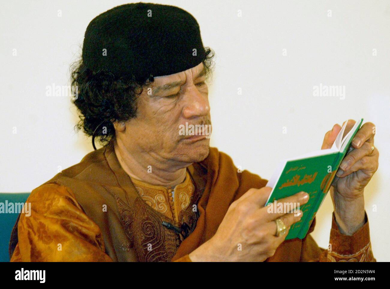 Libyan leader Muammar Gaddafi reads a green book during his debate on democracy with two Western scholars in the desert in Sebha March 2, 2007, in a move apparently designed to further the resumption of international ties following years of isolation. Speaking on the 30th anniversary of his declaration of a Jamahiriyah or state of the masses, Gaddafi said Libya was embracing globalisation and the outside world after years of sanctions but insisted his experiment in rule by town hall meetings was fairer than the West's ballot box democracy. REUTERS/Louafi Larbi (LIBYA) Stock Photo