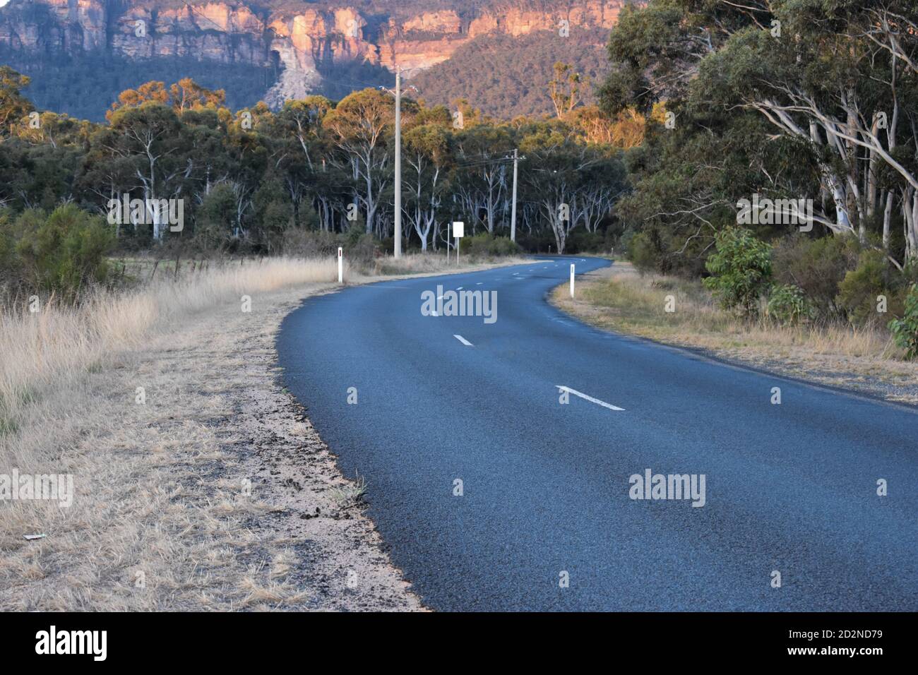 a winding road with the cliffs of the blue mountains in the background Stock Photo