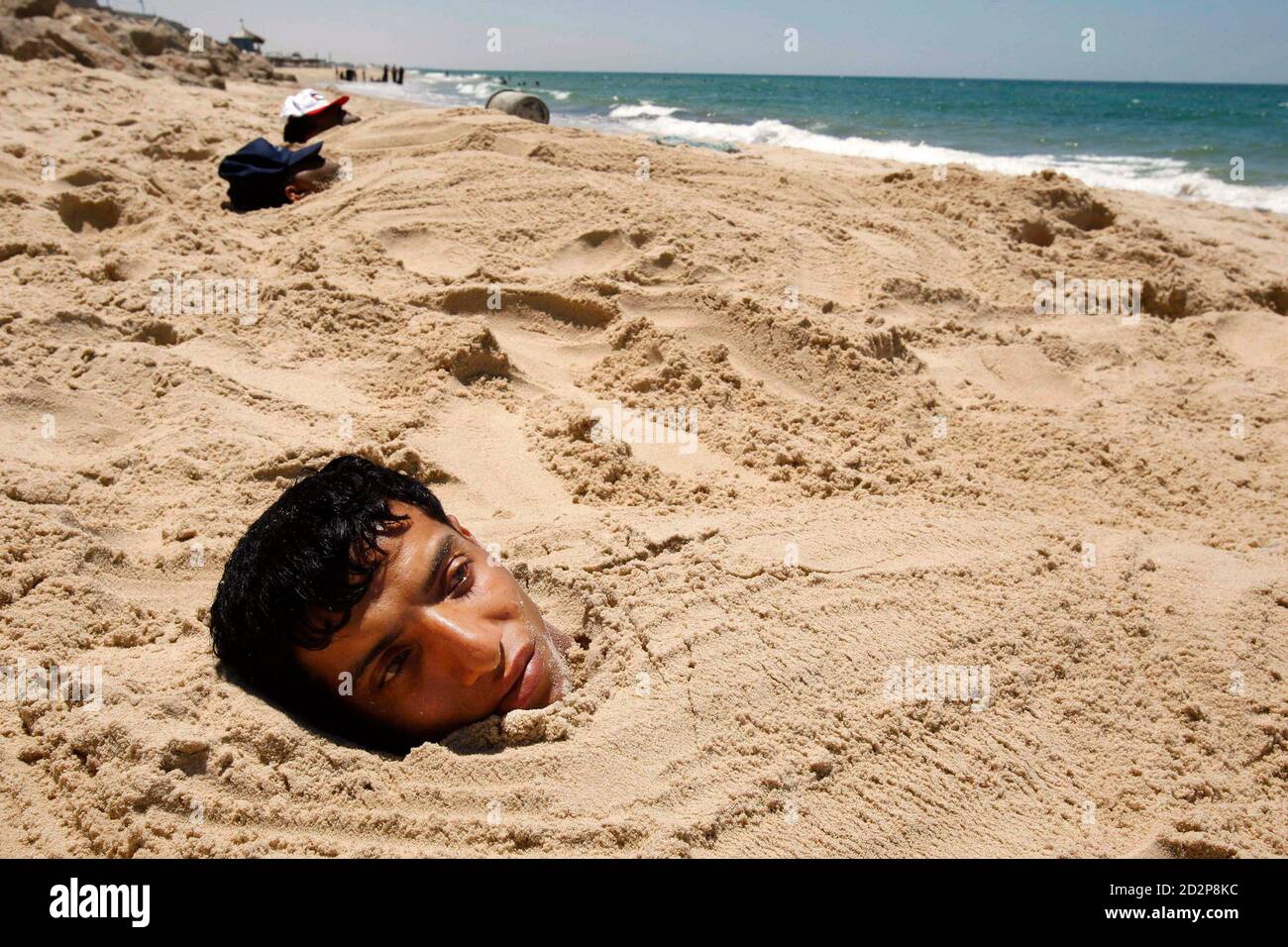 Человек без дна. Человек в песке на пляже. Человек закопанный в песок на пляже.