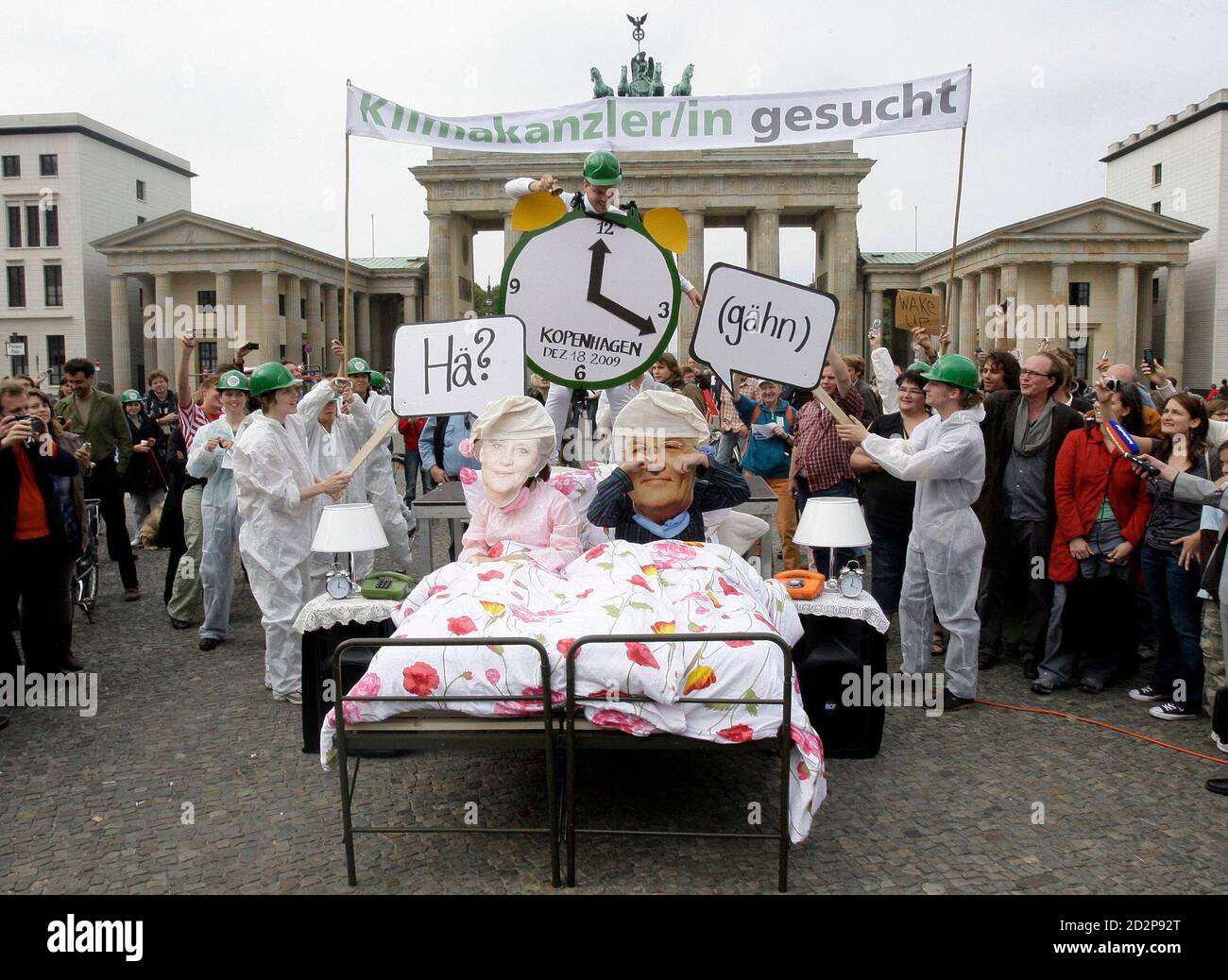 Climate activists of the global advocacy group AVAAZ, wearing masks depicting German Chancellor and leader of the Christian Democratic Union (CDU) party Angela Merkel and Germany's Foreign Minister and Social Democratic Party (SPD) candidate for chancellor Frank-Walter Steinmeier (R) lie in a bed in front of the Brandenburg Gate, during a protest in Berlin, September 21, 2009. On Monday AVAAZ took to the streets in five continents to set a sign for more engagement in climate policy. REUTERS/Tobias Schwarz (GERMANY POLITICS CONFLICT IMAGES OF THE DAY) Stock Photo