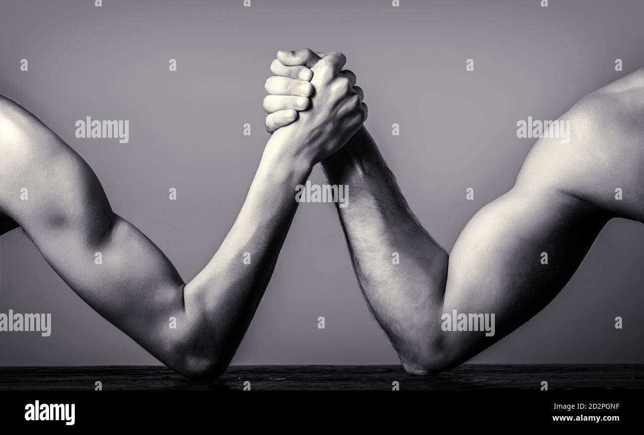 Two man's hands clasped arm wrestling, strong and weak, unequal match