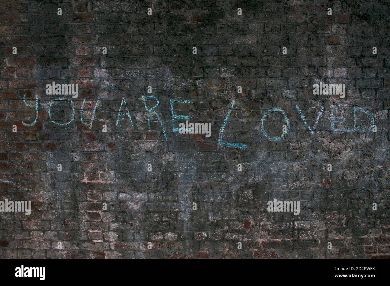 You Are Loved Written On A Dirty Brick Wall In London, UK Stock Photo