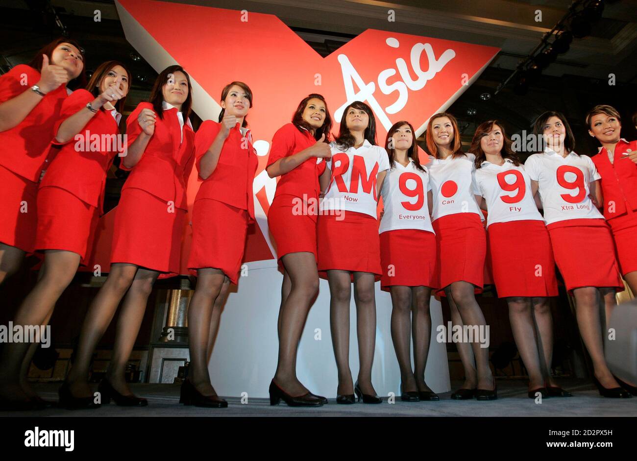 Malaysian budget carrier AirAsia stewardesses pose during the unveiling of plans for a low-cost longhaul service in Kuala Lumpur January 5, 2007. AirAsia Bhd on Friday announced plans to double its Airbus A320 fleet, with its major owners also unveiling plans for a long-haul low-cost airline that would help it fly beyond Asia.    REUTERS/Zainal Abd Halim (MALAYSIA) Stock Photo
