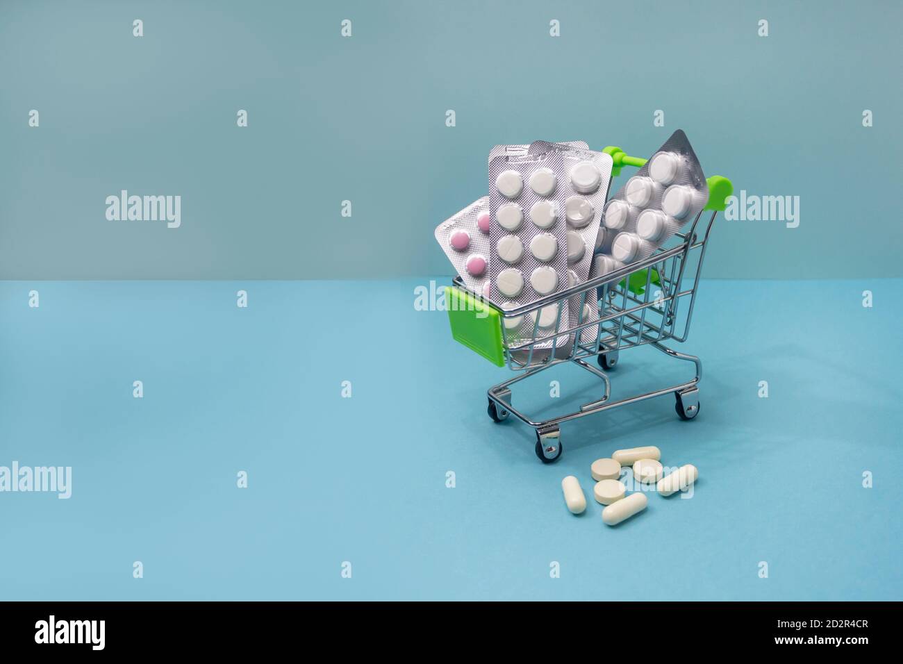 Medical shopping concept. Various pills and medicines in a shopping cart. Copy space on a blue background. Stock Photo