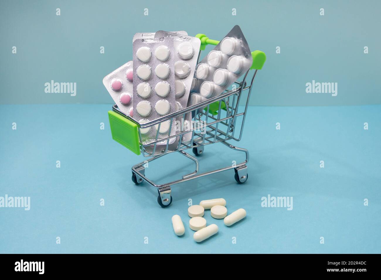 Buying medicines online. Home delivery. Medicines in shopping cart on blue background close-up. Stock Photo