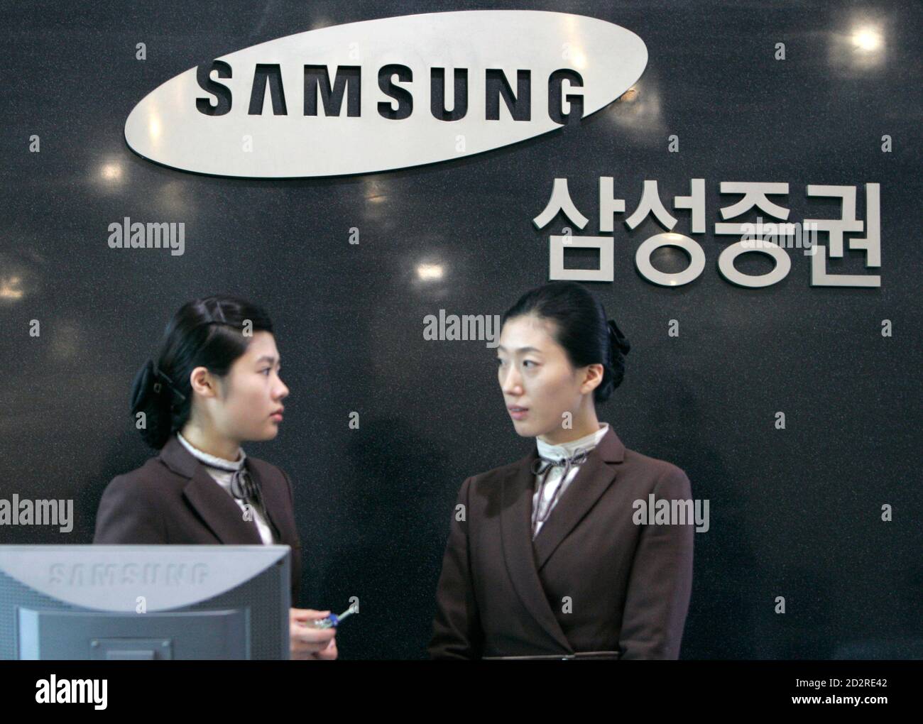 Employees of Samsung Securities talk in front of its logo at the unit's headquarters in Seoul November 30, 2007. South Korean prosecutors probing corruption at the Samsung Group raided its brokerage unit Samsung Securities on Friday and did not rule out further search and seizures at Samsung offices, an official said.  REUTERS/Jo Yong-Hak (SOUTH KOREA) Stock Photo
