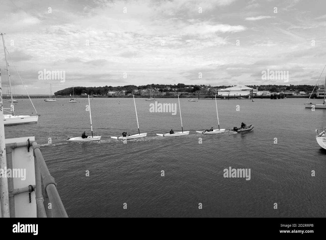 Sailing dinghies in a line under tow by RIB West Cowes seafront harbour Isle of Wight Stock