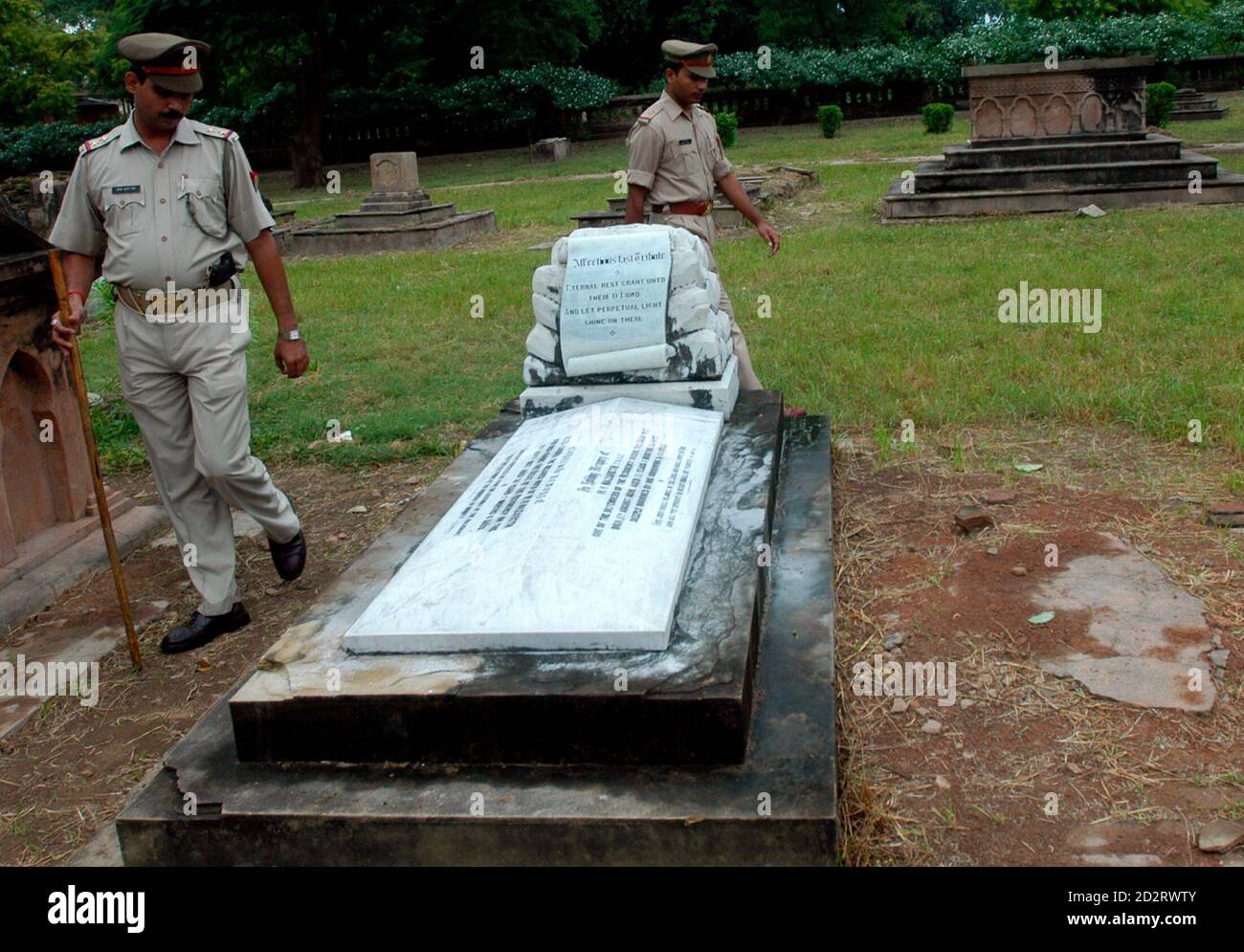 Police walk near a grave of a British soldier at the Residency in Lucknow September 24, 2007. A group of retired British soldiers and civilians visiting India have caused outrage during their trip to pay homage at sites where British soldiers died during the 1857 revolt against colonial rule.  REUTERS/Pawan Kumar (INDIA) Stock Photo