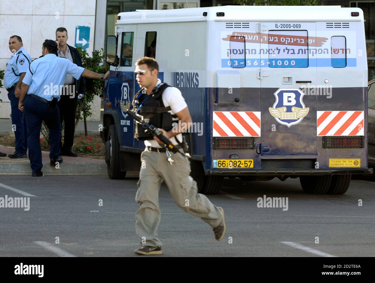 An Israeli security guard (C) runs near a truck loaded with Israeli  currency before its transfer to Gaza at the Erez crossing December 11,  2008. Israel allowed trucks carrying 100 million shekels ($