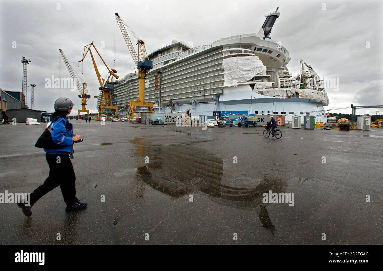 A visitor walks past the Royal Caribbean's Oasis of the Seas cruise ship which is under construction at the STX Europe shipyard in Turku August 27, 2009. The 225,000-ton ship will be the largest cruise vessel ever built and will be able to accommodate over 6,000 passengers. REUTERS/Bob Strong  (FINLAND SOCIETY TRAVEL) Stock Photo