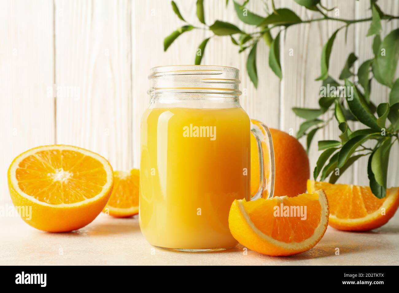 Glass jar with orange juice against white wooden background Stock Photo