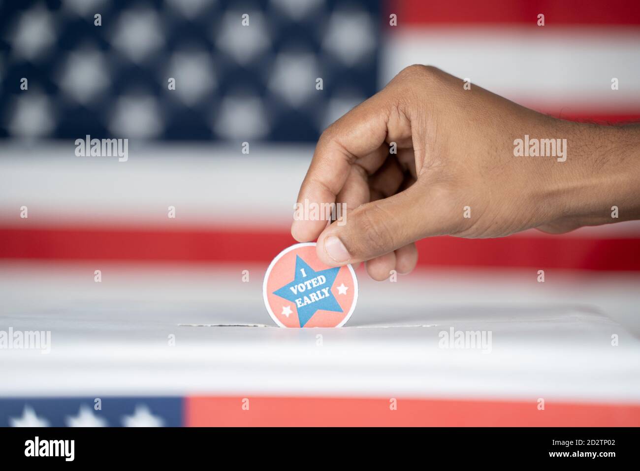 Close up of Hands placing I voted Early sticker inside the ballot box - Concept of Early voting in us election. Stock Photo