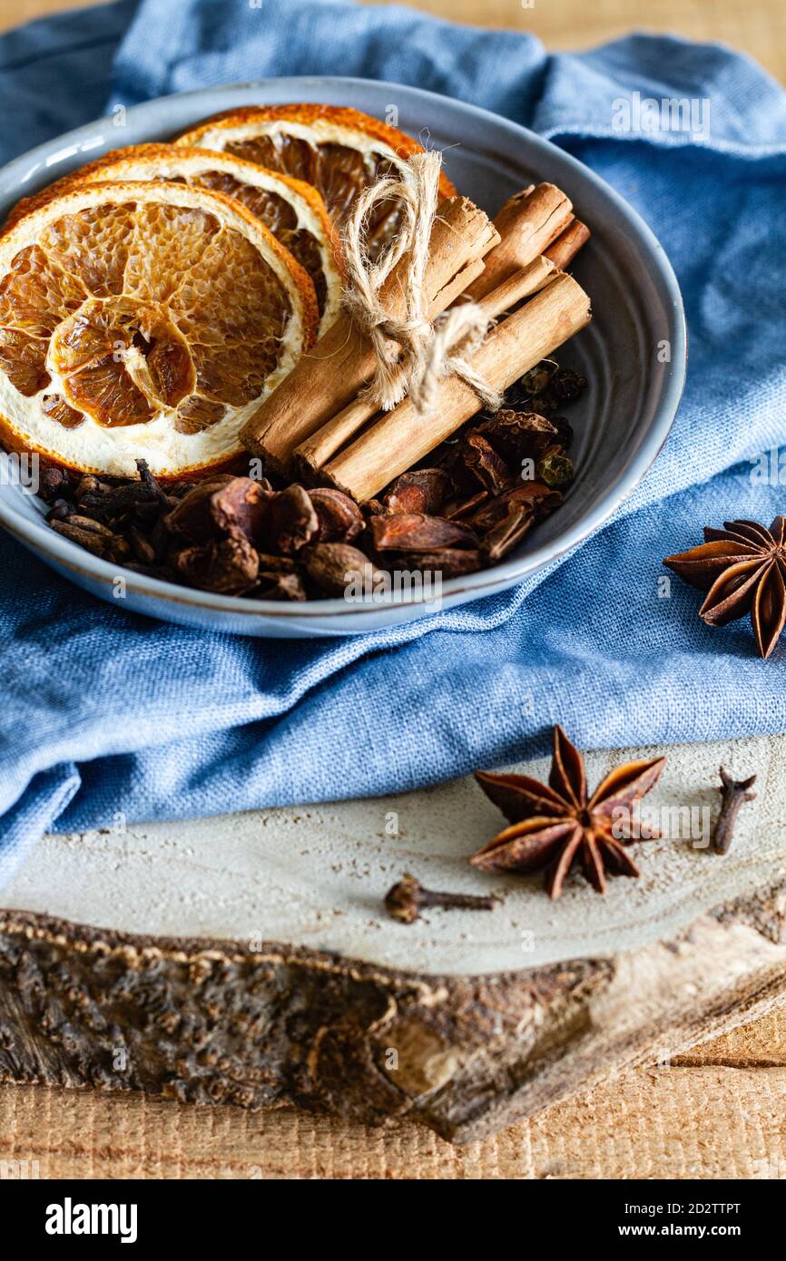 High angle of bowl with aromatic cinnamon sticks and dried oranges arranged on table with star anise and cloves Stock Photo
