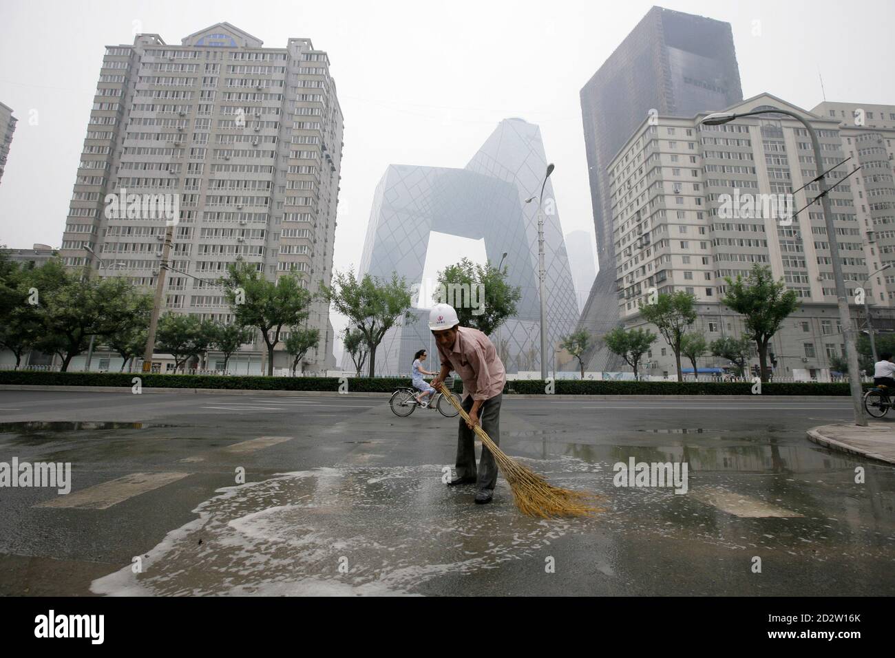 A worker sweeps water off a street at the Central Business District in Beijing July 16, 2009. China's annual GDP growth accelerated to 7.9 percent in the second quarter from 6.1 percent in the first quarter, as a surge in bank lending and government spending made it the best-performing major economy in the world. REUTERS/Jason Lee (CHINA BUSINESS) Stock Photo