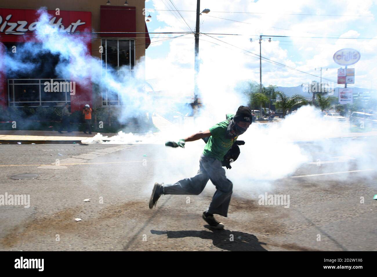 A supporter of Honduras' ousted President Manuel Zelaya kicks away a teargas canister during a protest near the site of negotiations to end the political crisis, in Tegucigalpa October 29, 2009. Zelaya and de facto rulers in power since a June coup returned to the negotiating table on Thursday, under pressure from U.S. officials who said time is running out to resolve the political crisis. REUTERS/Oswaldo Rivas (HONDURAS POLITICS CONFLICT) Stock Photo