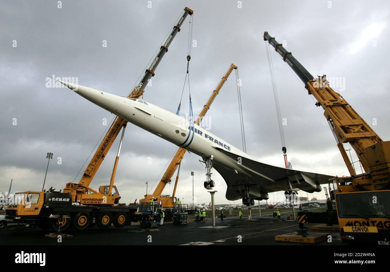 The retired Air France Concorde number 5 is lowered by cranes onto pylons on the tarmac at the Roissy-Charles de Gaulle Airport, north of Paris October 19, 2005. The retired Concorde is placed on permanent display in an inclined position to simulate the take off of the supersonic passenger jet. Stock Photo