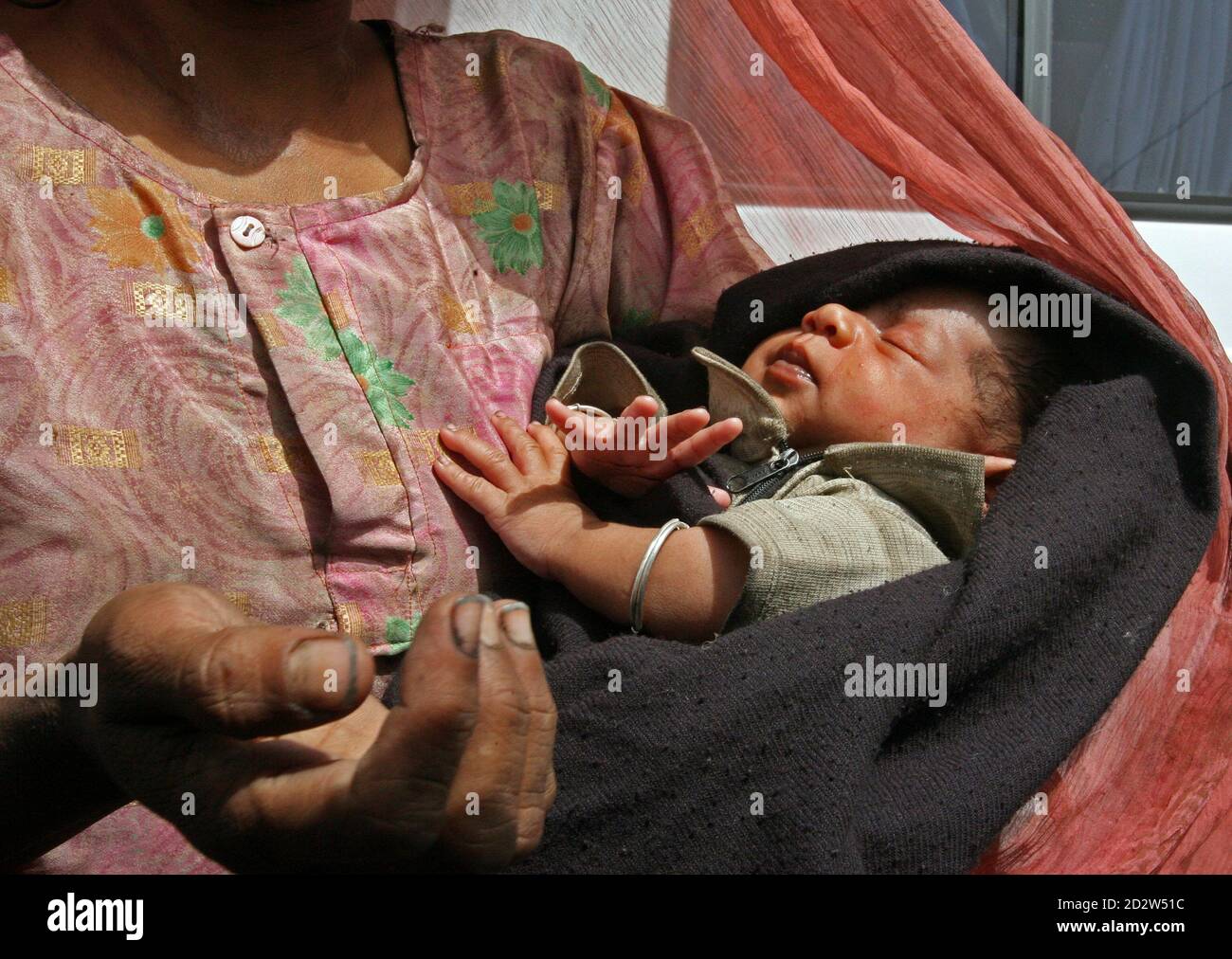 An Indian homeless woman waits for alms at a traffic intersection as she  holds a newborn baby in New Delhi March 26, 2006. [The Indian economy's  growth rate has kept an average