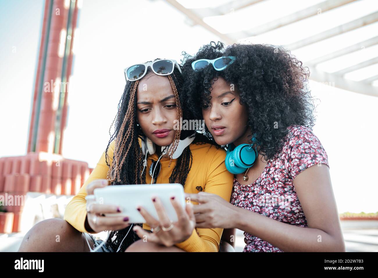 Laughing African American female with curly hair and black Woman with braids sitting on promenade in summer and watching funny video together on cellphone Stock Photo - Alamy Laughing African American female with curly hair and black Woman with braids sitting on promenade in summer and watching funny video together on cellphone Stock Photo - Alamy