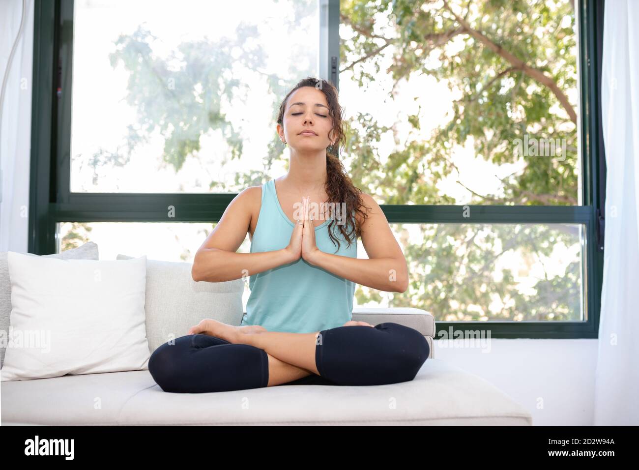 Concentrated flexible female sitting with crossed legs doing yoga in