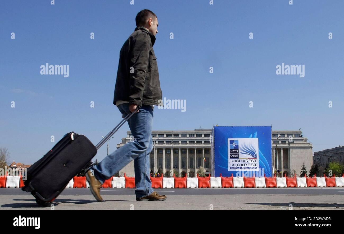 A man walks in Victoria square in front of a banner advertising upcoming NATO Summit during a rehearsal for traffic restrictions in Bucharest March 29, 2008. Romania's capital city Bucharest faces stringent security measures and traffic chaos during the April 2-4 NATO Summit. More than 30,000 personnel have been drafted to secure the bustling city and 6,500 delegates and journalists. REUTERS/Bogdan Cristel (ROMANIA) Stock Photo