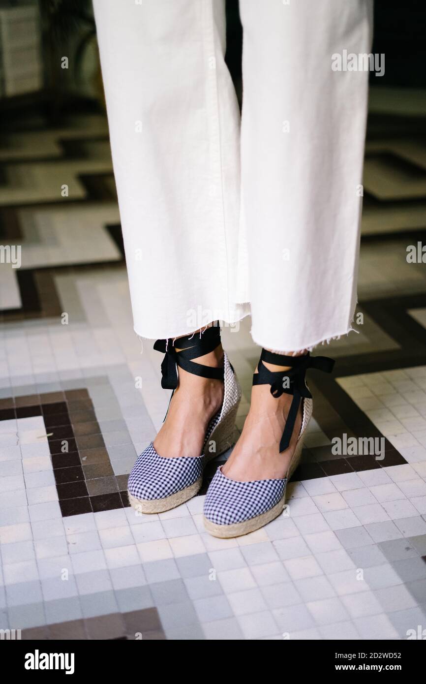 Side view of anonymous crop female wearing wedge sandals and trendy jeans standing in modern flat Stock Photo