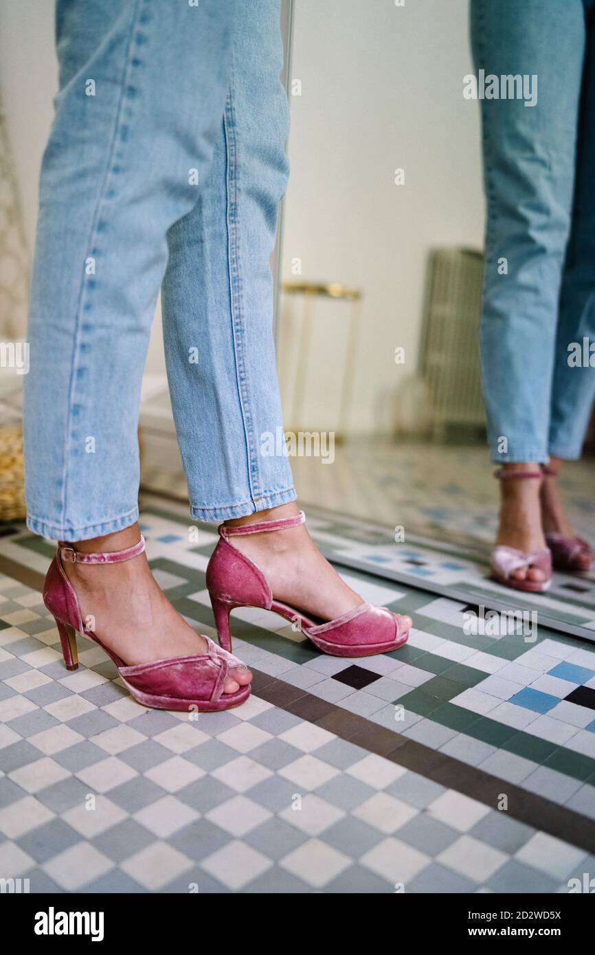 unrecognizable female wearing jeans and open toe heels standing in front of mirror in modern apartment Stock Photo