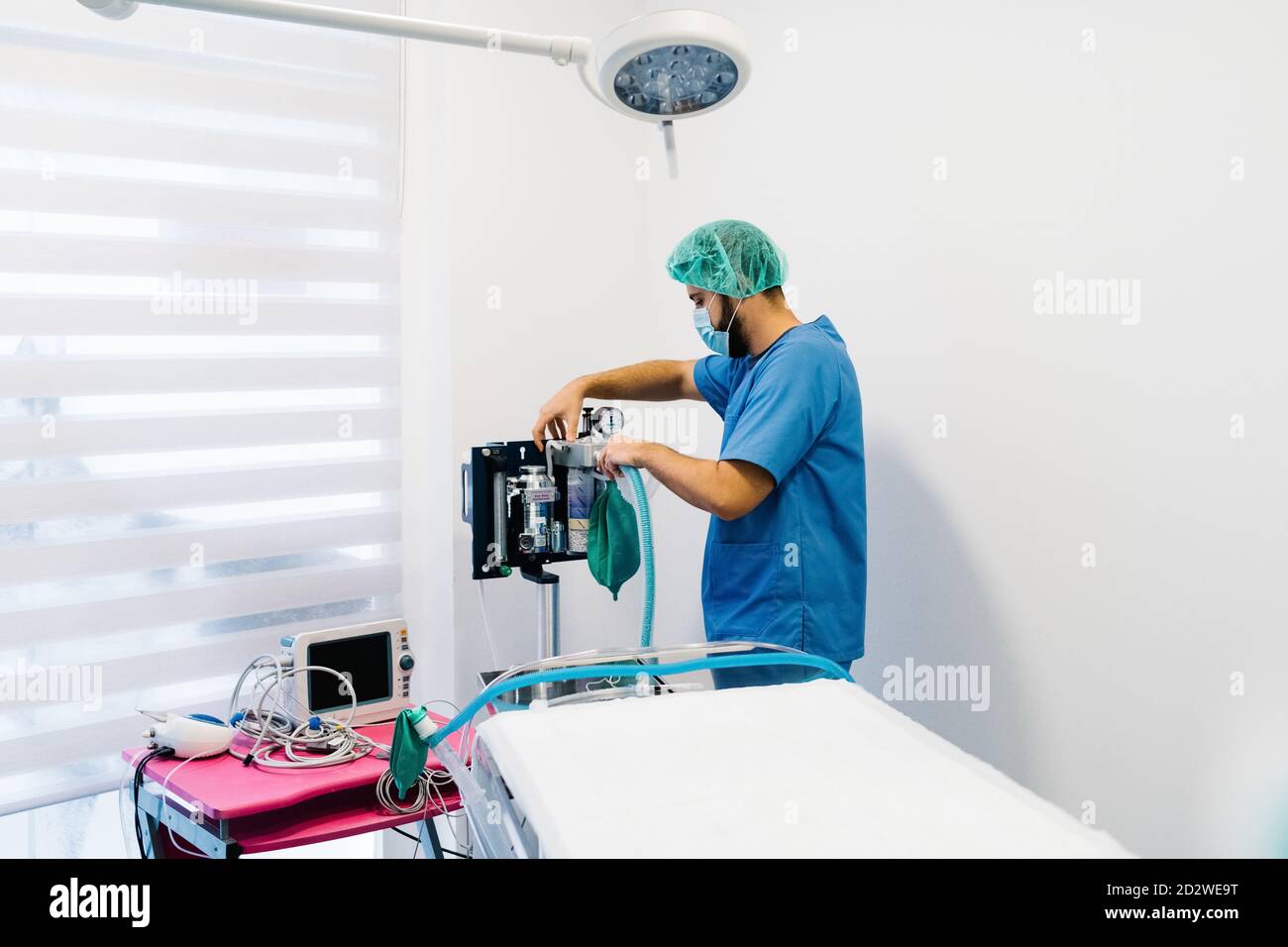 Side view of male vet doctor in uniform and mask preparing anesthesia