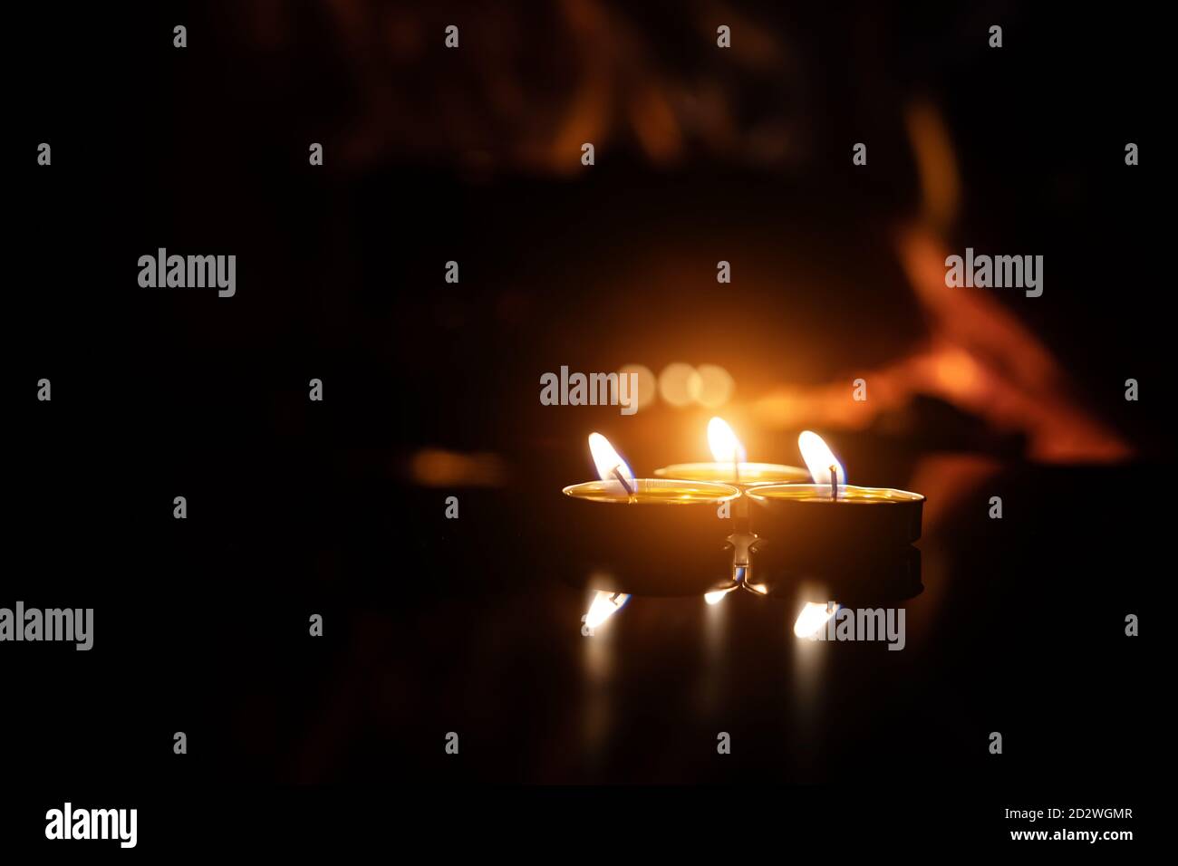 three candles on a black background with a fireplace flame Stock Photo ...