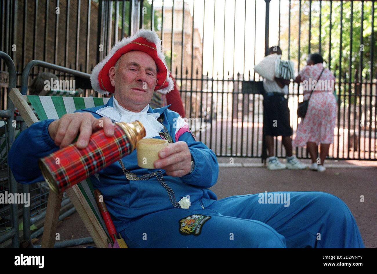 'Sir' Gary Baldi pours some tea from a flask after erecting his deck chair outside the gates of Clarence House in London today (Thur) in the hope of glimpsing the Queen Mother during her 95th birthday celebrations tomorrow (Fri). Mr Baldi, from Wandsworth, London, joined several other Royal watchers camped outside the gates ahead of Friday's regal event. Stock Photo