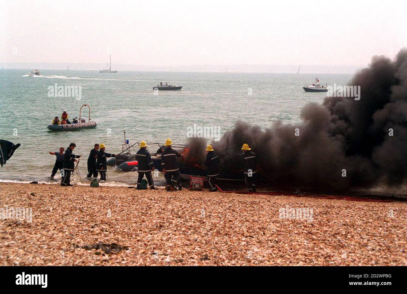 Rescue workers at the scene where the 28ft Warlord Express, an upmarket yacht, was engulfed in flames after it was set on fire by children, causing 20,000 worth of damage, at Stokes Bay, Portsmouth, Hants. See PA Story CRIME Boat Stock Photo