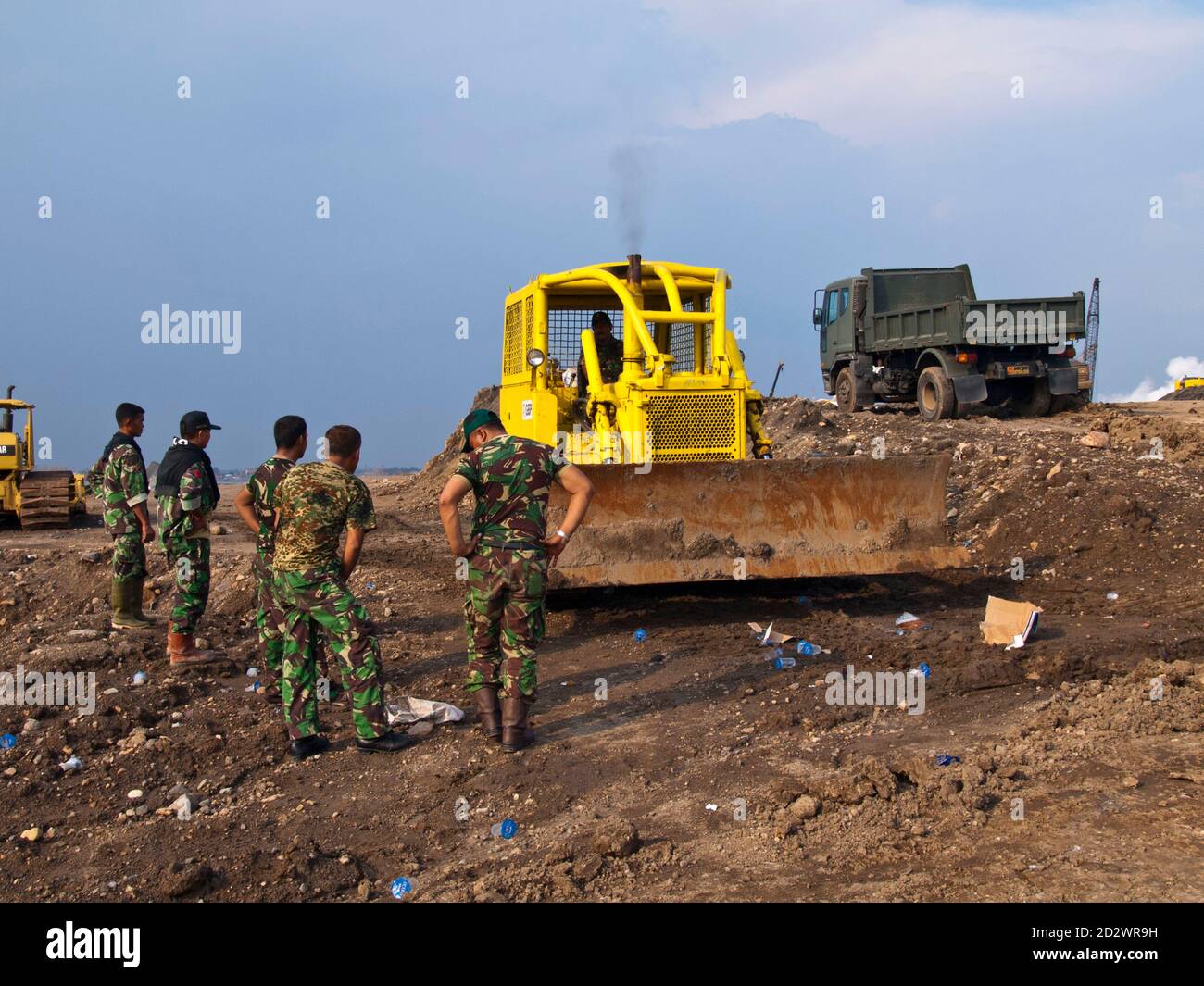SIRING, SURABAYA, JAVA, INDONESIA - FEB 22, 2007: Catepiller and soldiers on a dam which was built to prevent the village of Siring near Surabaya,  Ja Stock Photo
