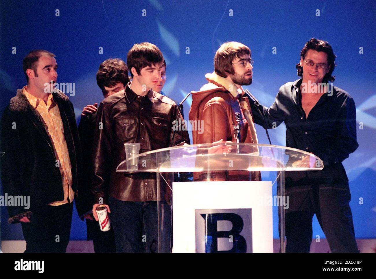 Manchester pop group Oasis accept the Brit award for Best Video (for 'Wonderwall') from Inxs frontman Michael Hutchence (left) at a star-studded ceremony at London's Earl's Court. Liam Gallagher, with beard, confronted Hutchence, once linked to Gallagher's present girlfriend Patsy Kensit, and said 'Has-beens shouldn't present awards to going-t-be's'. Stock Photo