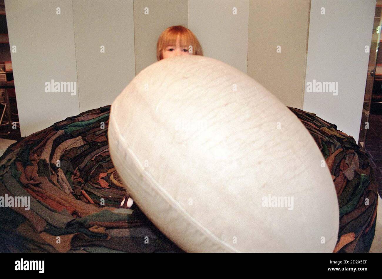 Harry Edmonds, aged 18 months, from London, sits in 'La Cova', designed by Giovanni Ruffi, a giant nest upholstered in layered pieces of cloth, complete with an egg cushion, which is expected to realise between  6,000 to  8,000 when it auctioned by Bonhams. Stock Photo
