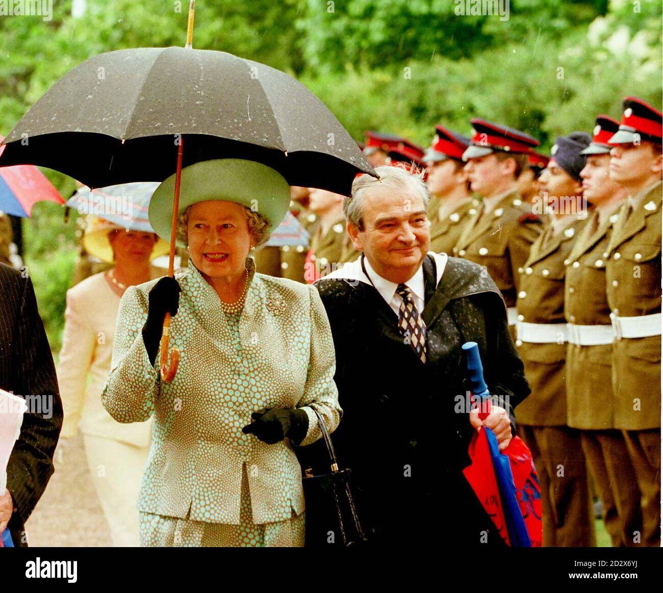 The Queen shields herself from unseasonal rain as she arrives with headmaster Neville Ireland today (Friday) at Loughborough Grammer School to help celebrate its quincentenary by opening a new English and Drama centre at the school. Rota picture by Times. Stock Photo