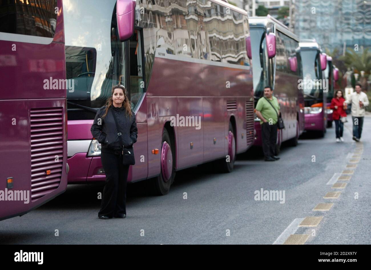 Spanish tourists stand next to tourist buses that are stuck during a  24-hour strike at the port of Piraeus, near Athens April 26, 2010. Dockers  at Greece's largest ports stopped work on