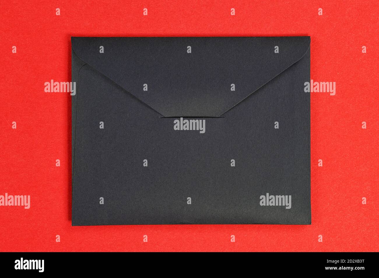 Black closed cardboard envelope. Isolated on red, clipping path ...