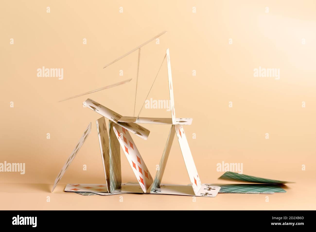 Crashed house of cards. Falling cards on beige background Stock Photo