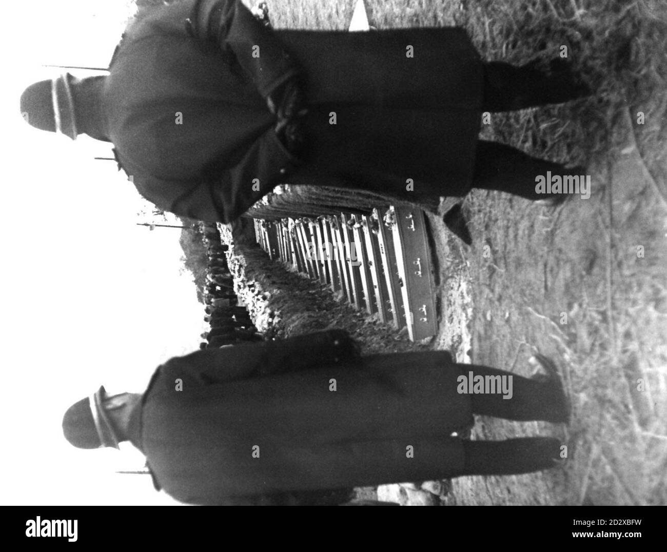 Library file 124814-63 dated 27/10/66: Between the figures of the guardian policeman the sad row of small coffins rests in the common grave in a hillside cemetery above Aberfan South Wales. 79 of the 116 children and one  of the 28 adults, a woman, victims of the colliery tip disaster were laid to rest in a mass funeral, 30 years ago today. See PA Story ABERFAN Anniversary. PA Photos. Stock Photo