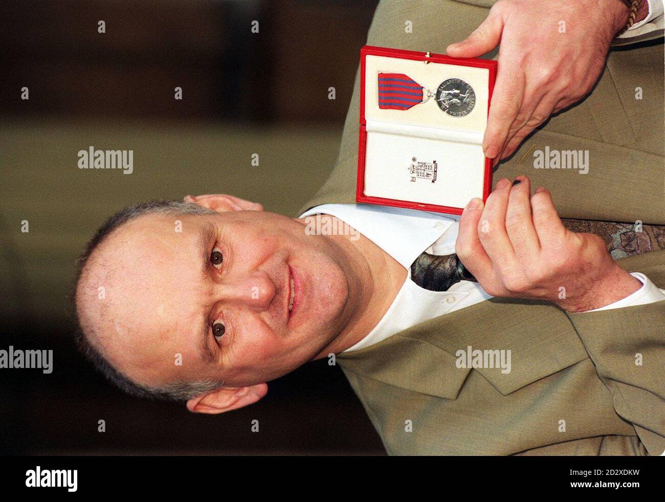 Christopher Crawshaw proudly displays the George Medal, which was presented to his family by the Queen at Buckingham Palace today (Tuesday),  in recognition of his late brother Jack's gallantry. Retired grocer Jack Crawshaw, 51, and off -duty fireman Michael Mee, 48, tried to save Tracey Pattison, 11, from the freezing waters of Hemsworth Water Park, near Pontefract, West Yorkshire, last December. All three drowned. See PA Story DEATH Medal. Photo by John Stillwell/WPA Rota.   Stock Photo