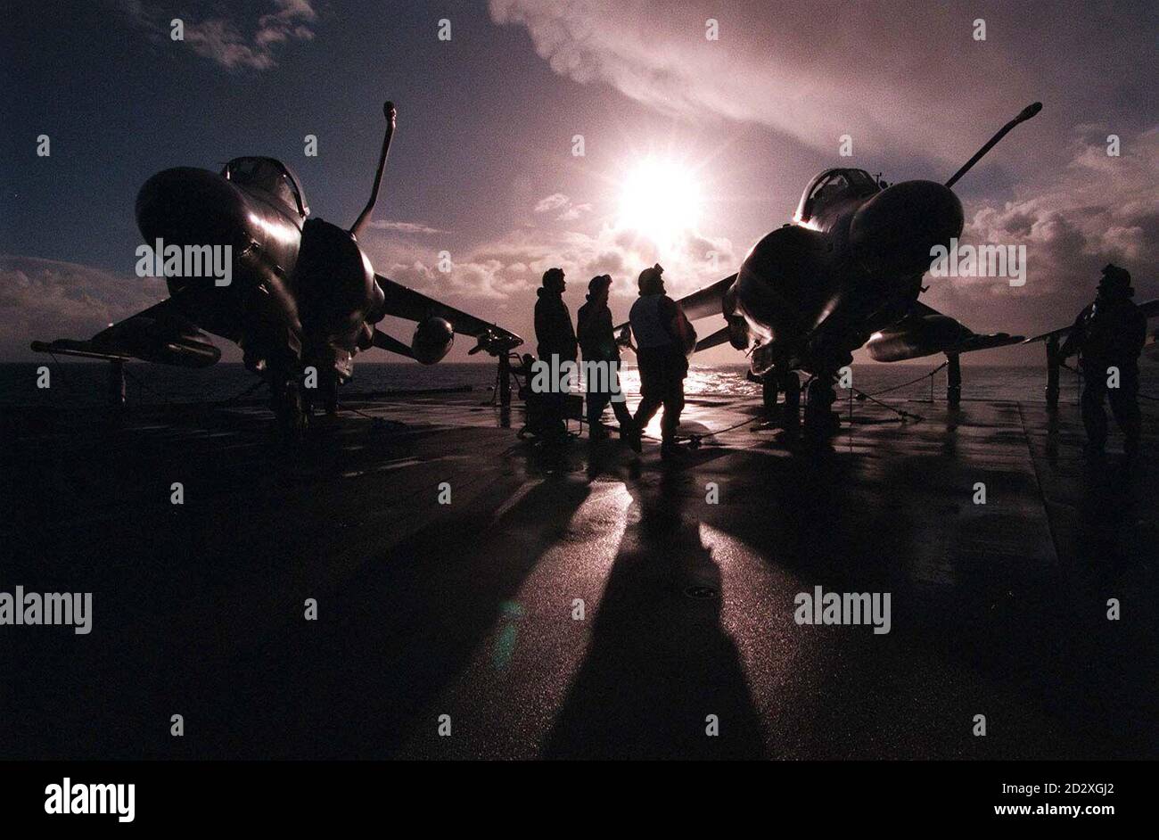 Navy pilots stand by their Sea Harriers as the sun rises over the Bay of Biscay behind HMS Illustrious as the aircraft carrier sails south on her way to join with other naval vessels for the Ocean Wave training exercise. PA photo by Paul Cowpe/DPRN. Stock Photo