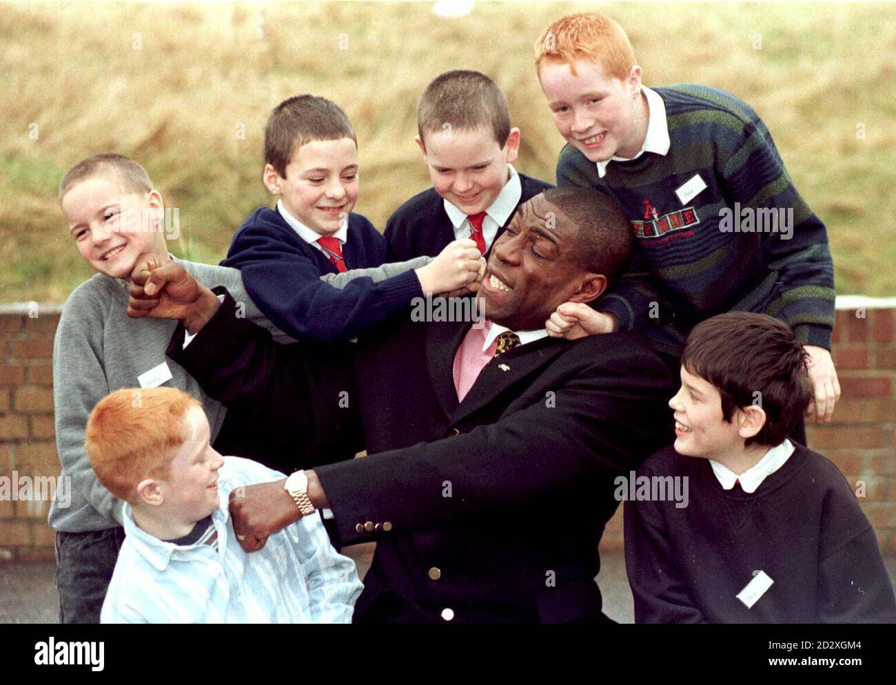 Former heavyweight champion Frank Bruno swaps playful punches with children at the notorious Riding School in Halifax this morning (Thursday). The jovial boxer was invited to the West Yorkshire school by a teacher who heard him make a pantomime gag about the school's troubles. Photo by Paul Barker/PA. SEE PA STORY SHOWBIZ Bruno. Stock Photo