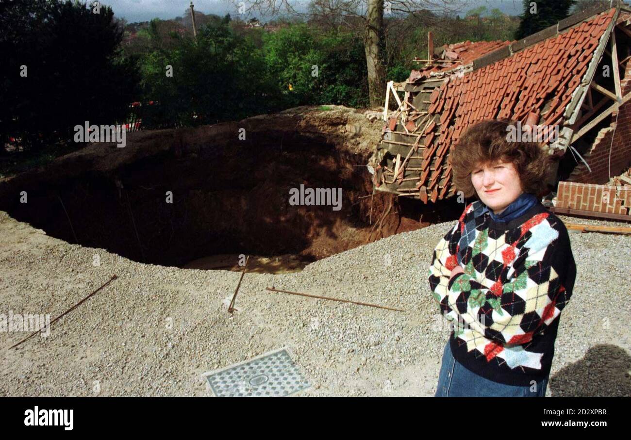 Jane Sherwood Britton, 32, stands beside the hole, 70 feet across and 100 feet deep, where her garage used to be, at her house in Ripon, North Yorkshire today (Thursday). The hole appeared before her eyes last night, when Mrs Britton called her children inside. The collapse is believed to have been caused by a geological fault in the area. An expert from the British Geological Survey is expected on the scene later today. Photo by Paul Barker/PA Stock Photo
