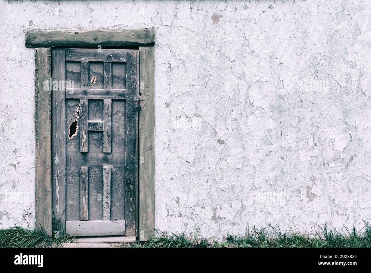 Old wooden door in the wall with cracked paint texture, copy space