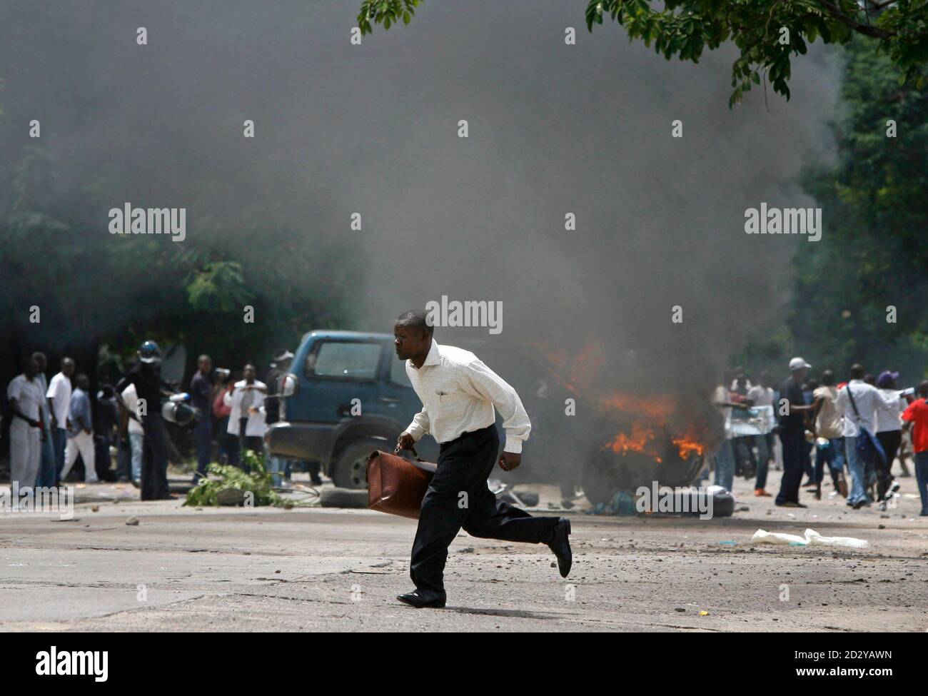 A man runs in front of an European Union vehicle, burnt by an angry mob of  supporters of Congolese presidential hopeful Jean-Pierre Bemba after a  gunbattle, in Kinshasa November 21, 2006. Gunmen