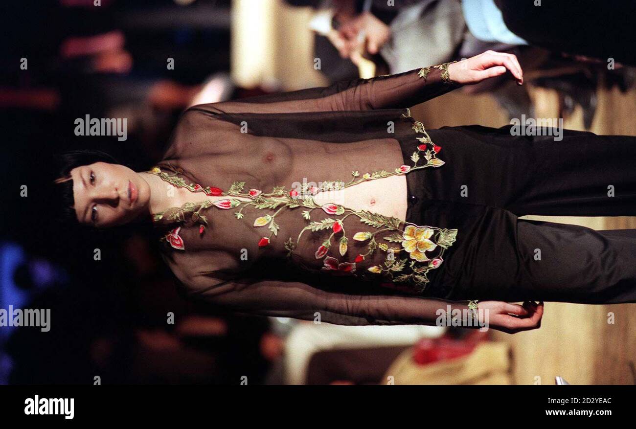 An oriental model wears a sheer blouse with flower embroidered edges and dark trousers from Justin Oh's winter collection during London Fashion Week, today (Tuesday).  Photo by Neil Munns/PA. Stock Photo