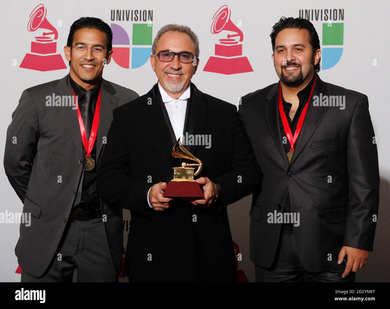 Emilio Estefan, husband of singer Gloria Estefan, poses with his award won  for Best Traditional Tropical Album for "90 Millas", and two guests at the  9th annual Latin Grammy Awards in Houston,