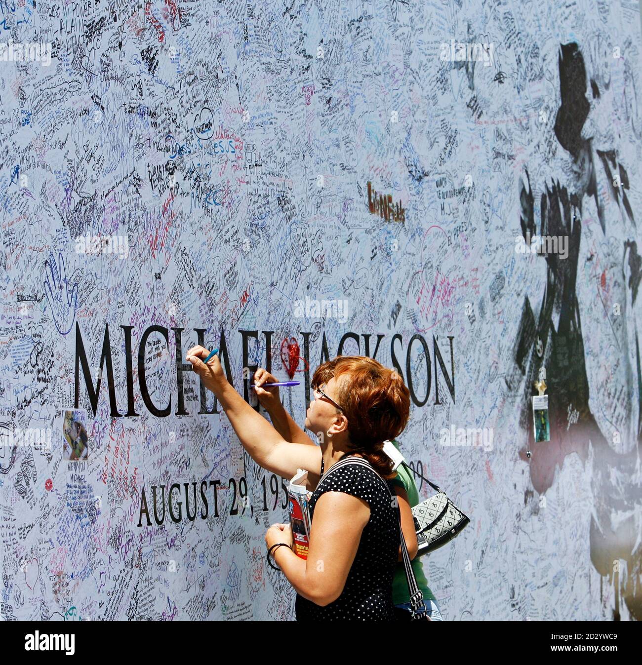 Fans sign a large Michael Jackson poster outside Staples Center in Los  Angeles July 6, 2009. The memorial for the pop star will be held at Staples  Center in Los Angeles July