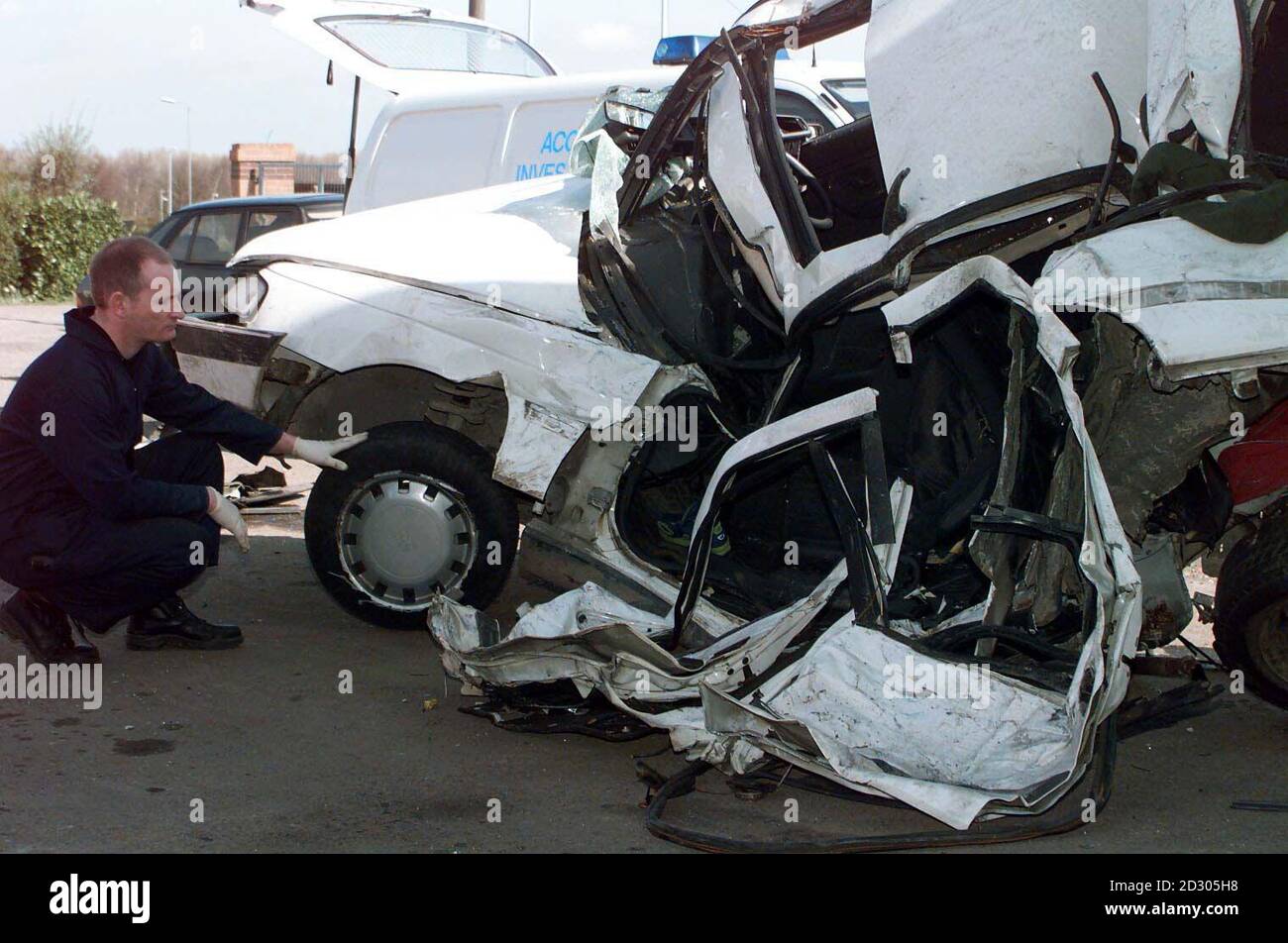 A police accident investigation officer inspects the remains of the car in which three teenagers