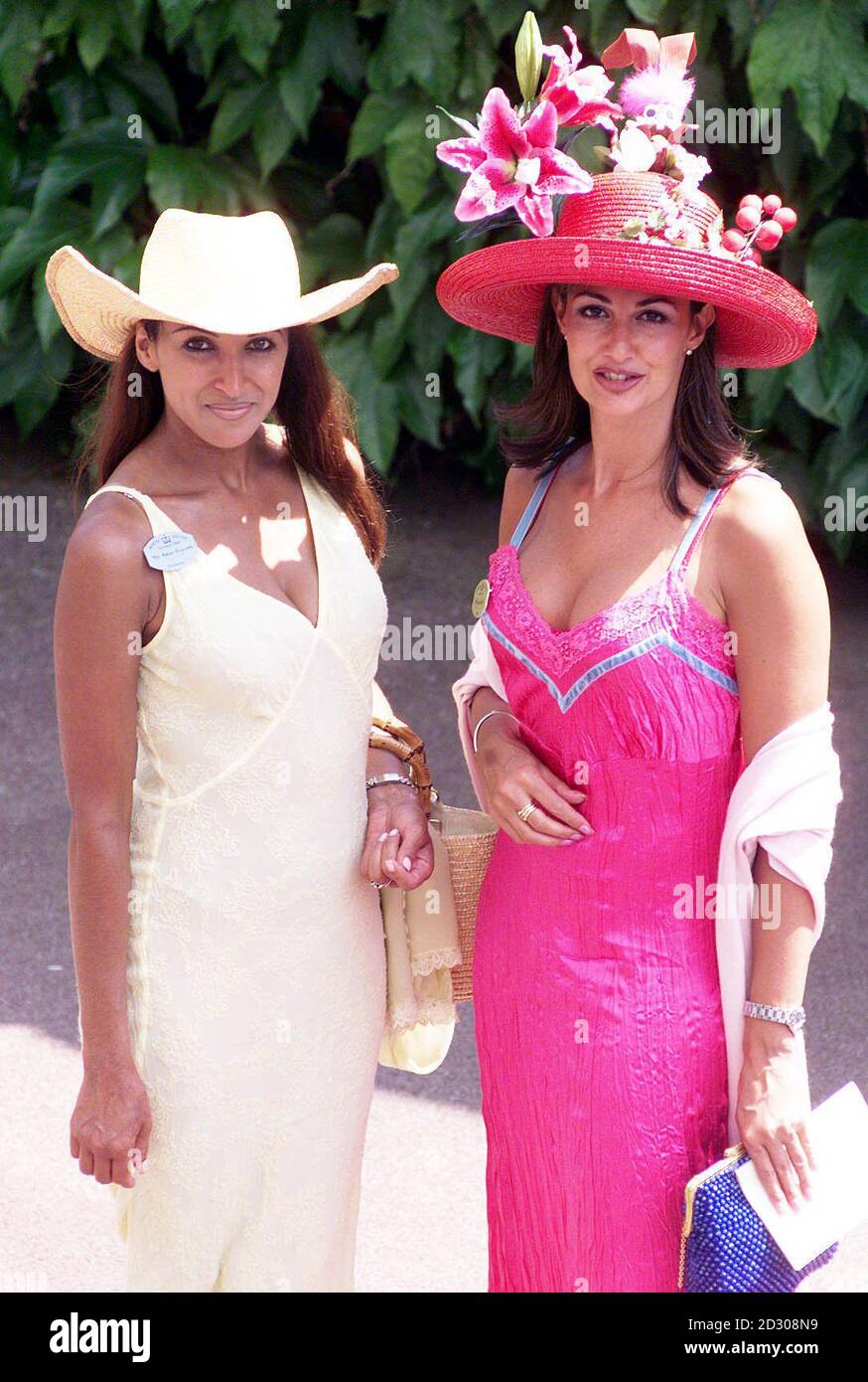 Kimberley Cowell in a red hat (right) and Jackie St. Clair in a Stetson at Ascot race course on the second day of the annual Royal race meeting.  Stock Photo